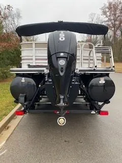 Slide: The Image of 2023 Ranger Reata 223C pontoon boat, rear view with outboard motor, parked on a road. - 2