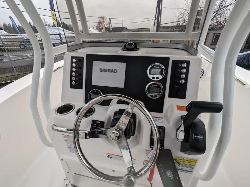 Slide: The Image of 2024 Robalo R200 Center Console boat dashboard with Simrad electronics and steering wheel. - 7