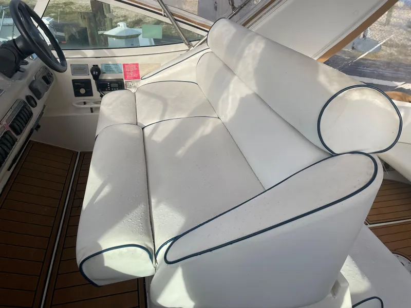 Slide: The Image of 2004 Cruisers Yachts 320 Express helm seating with white upholstery and blue piping. - 14