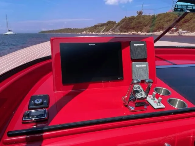 Slide: The Image of VanDutch 40 yacht dashboard with navigation system, controls, and cup holders, docked near a scenic coastline. - 9