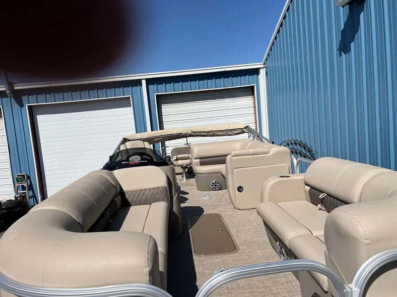 Slide: The Image of 2023 Sun Tracker SportFish™ 22 XP3 pontoon boat with beige seating, docked near blue storage units. - 17