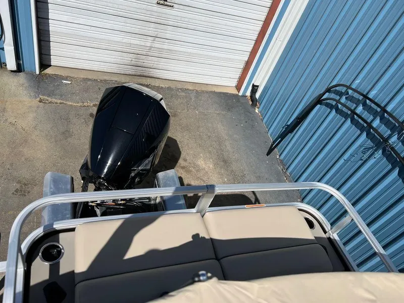 Slide: The Image of 2023 Sun Tracker SportFish™ 22 XP3 pontoon boat with outboard motor, docked near blue metal building. - 2