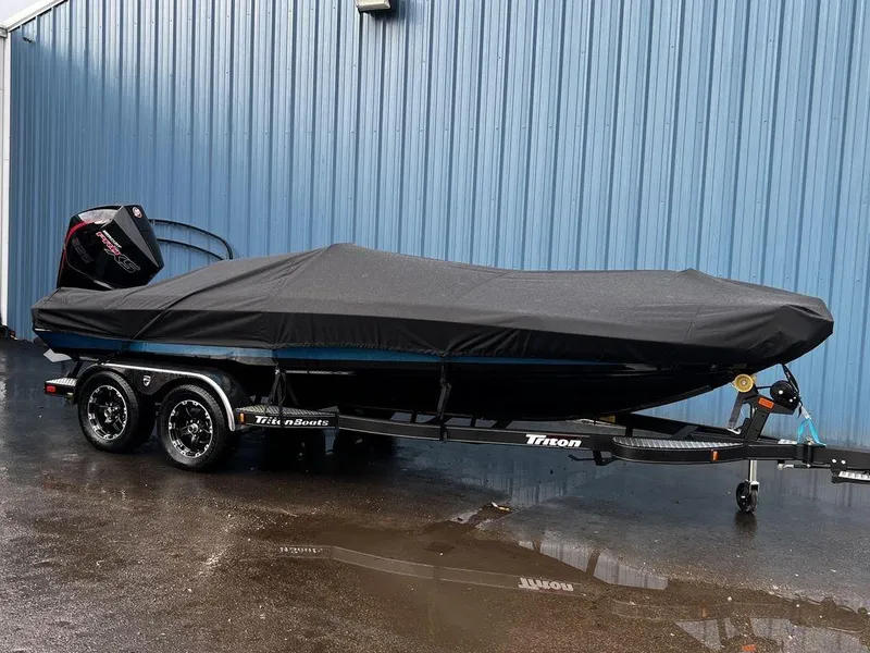 Slide: The Image of 2017 Triton 19 TrX boat with cover on trailer, parked by blue wall. - 3
