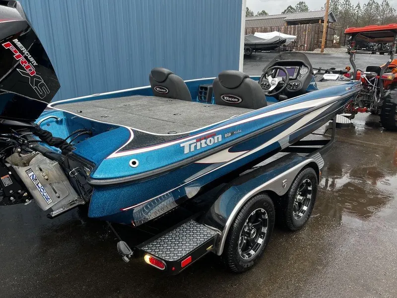 Slide: The Image of 2017 Triton 19 TrX bass boat with dual console and trailer in a wet parking lot. - 4