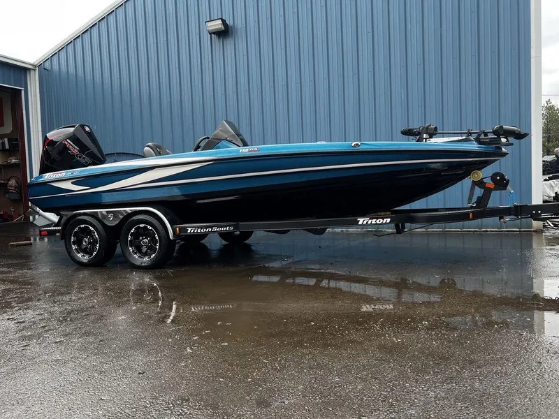 Slide: The Image of 2017 Triton 19 TrX boat on trailer, parked outside blue building. - 7