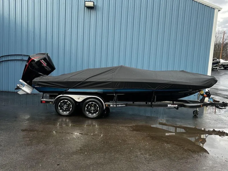 Slide: The Image of 2017 Triton 19 TrX boat with cover on trailer, parked by blue building. - 9