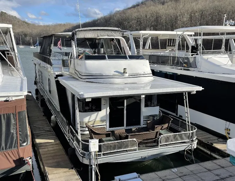 The Image of Sumerset 16x75 houseboat, year 2000, docked on a serene lake with surrounding forest. - 0