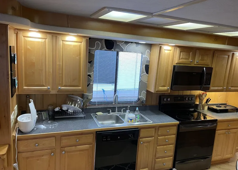 Slide: The Image of Modern kitchen in 2000 Sumerset 16x75 houseboat with wooden cabinets and black appliances. - 13