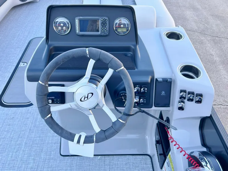 Slide: The Image of 2024 Harris Sunliner 250 boat dashboard with steering wheel and controls. - 2