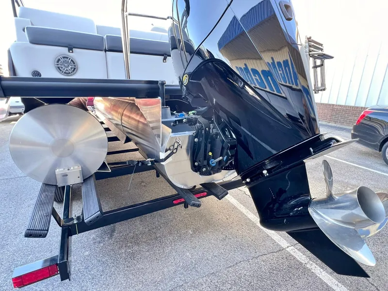 Slide: The Image of 2024 Harris Sunliner 250 boat engine and propeller detail in a parking lot. - 26