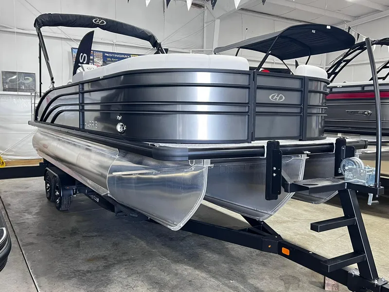 Slide: The Image of 2024 Harris Sunliner 250 pontoon boat in showroom, sleek design, black and silver finish. - 27