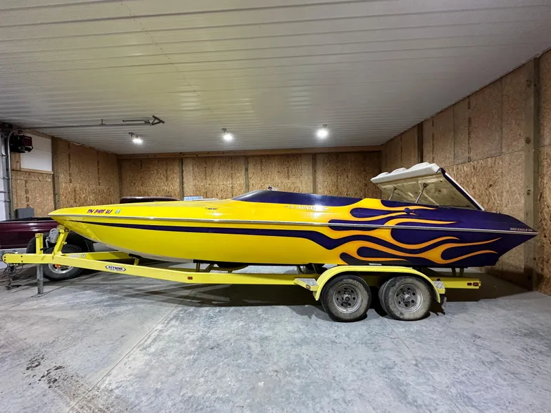 Slide: The Image of 2005 Eliminator 260 Eagle XP boat with yellow and purple flame design in a garage. - 1