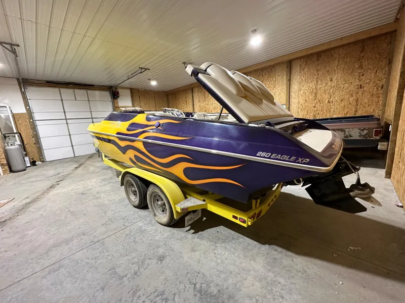 Slide: The Image of 2005 Eliminator 260 Eagle XP boat with vibrant flame design in a garage. - 5