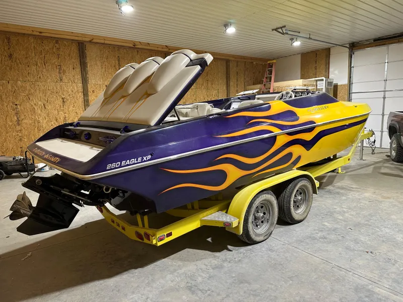 Slide: The Image of 2005 Eliminator 260 Eagle XP boat with vibrant flame design in a garage. - 6