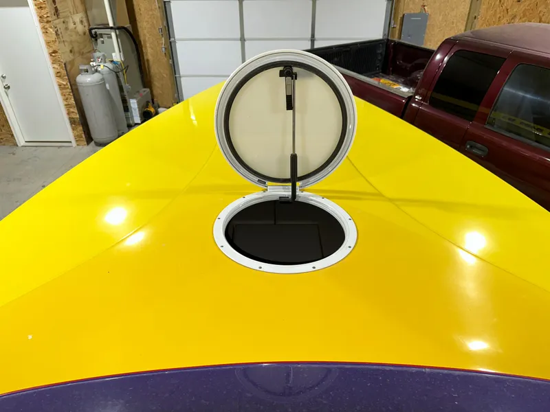 Slide: The Image of 2005 Eliminator 260 Eagle XP boat with yellow and purple deck, open hatch in garage. - 9