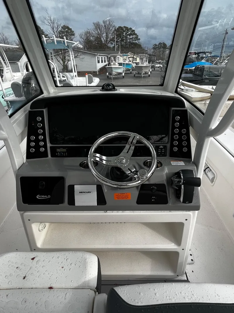 Slide: The Image of 2024 Robalo 266 Cayman boat dashboard with steering wheel and control panel. - 13