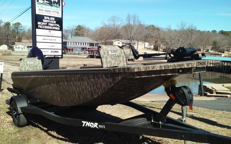 Slide: The Image of 2023 Thor Lake Hammer Elite boat on trailer near lake and boat rental sign. - 6