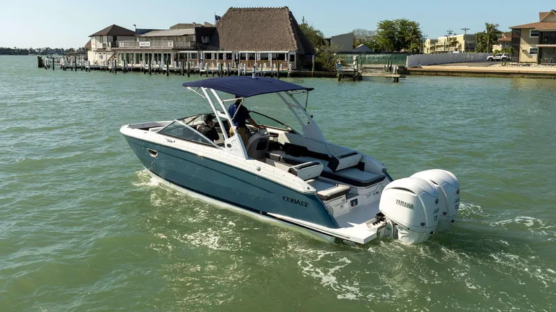 Slide: The Image of 2023 Cobalt R8 boat cruising on a sunny day near a waterfront building. - 2