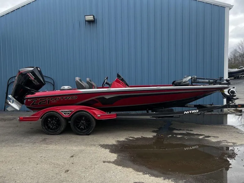 The Image of 2023 Nitro Z21 XL Pro bass boat in red and black, parked on a trailer. - 1