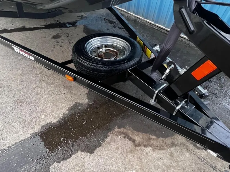 Slide: The Image of 2020 Triton 18 TX boat trailer with spare tire on wet pavement. - 12