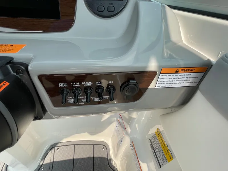 Slide: The Image of Control panel of 2024 Chaparral 23 SSi OB boat with warning labels and switches. - 27