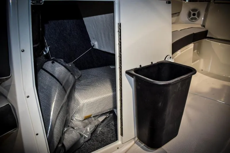 Slide: The Image of 2023 Yamaha Boats AR220 interior storage compartment with black trash bin. - 31