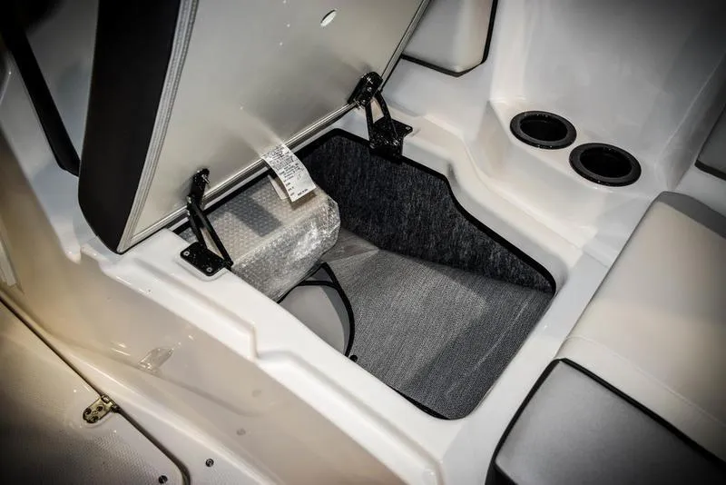 Slide: The Image of 2023 Yamaha Boats AR220 storage compartment with open seat and cup holders. - 35