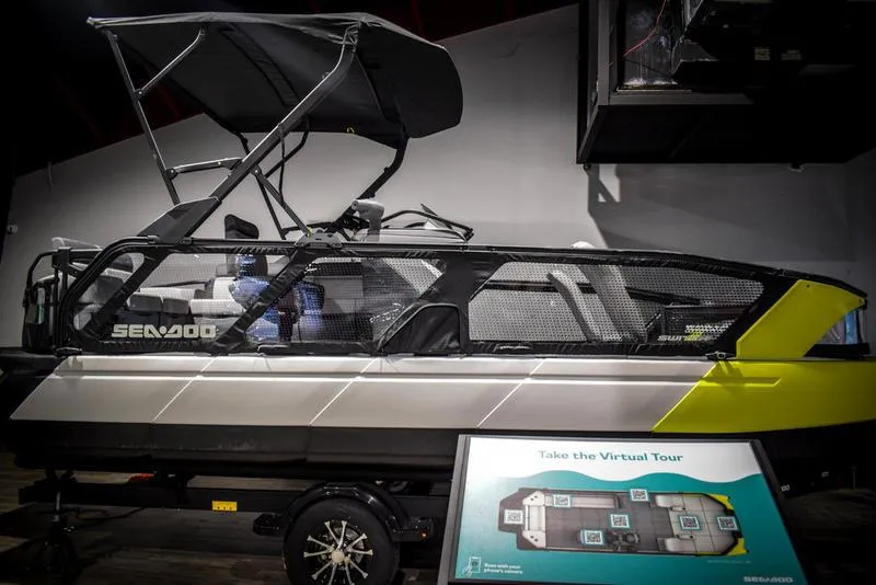 Slide: The Image of 2022 Sea-Doo Switch Sport 21 pontoon boat on display indoors. - 3