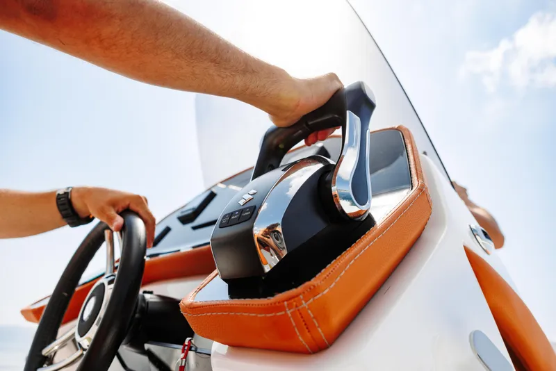Slide: The Image of Close-up of hands operating the throttle and steering wheel of a 2025 2 Bar 8.2 boat. - 31
