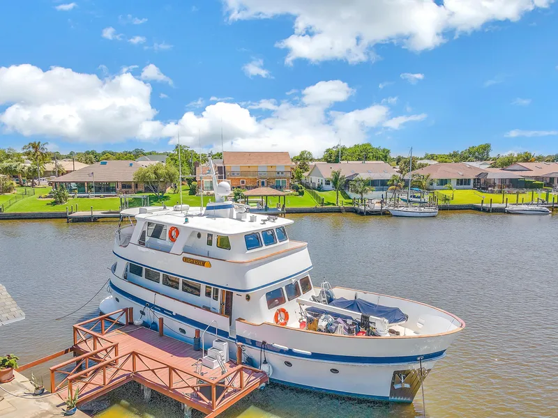 Slide: The Image of Cheoy Lee Expedition 70 yacht docked by waterfront homes, under a clear blue sky. - 34