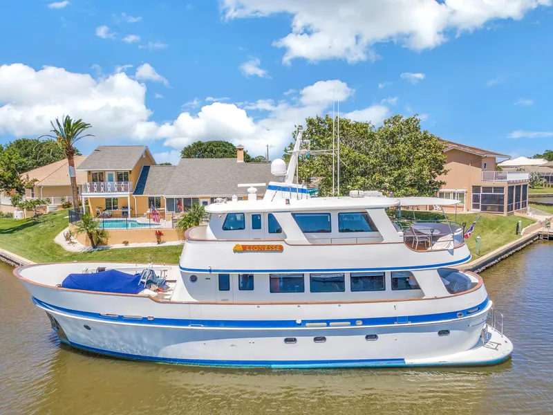Slide: The Image of Cheoy Lee Expedition 70 yacht, 2001 model, docked near waterfront homes under a clear blue sky. - 47