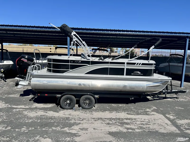 Slide: The Image of 2023 Bennington 21SXSRC pontoon boat on trailer under a metal canopy. - 0