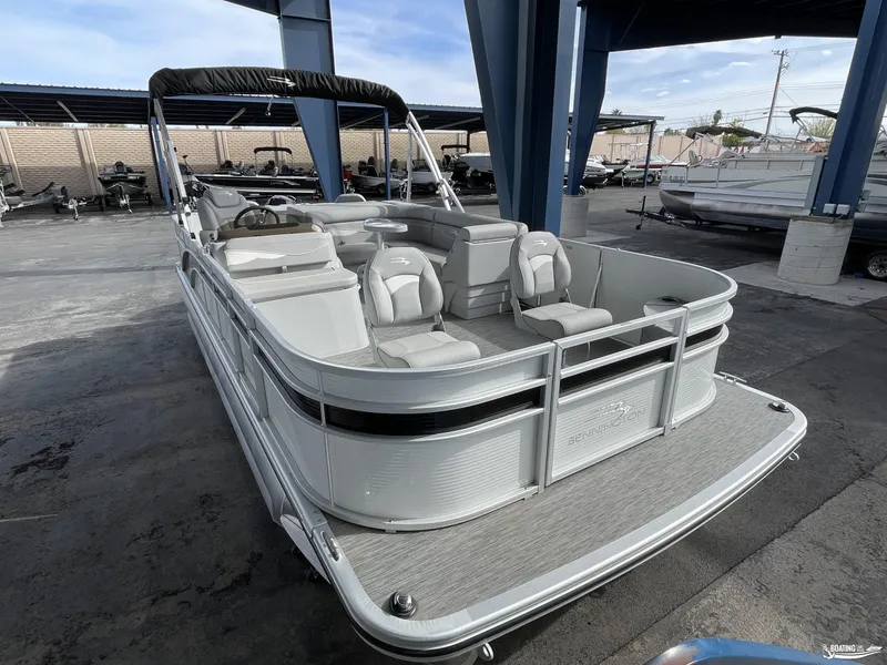 Slide: The Image of 2023 Bennington 21SF pontoon boat with spacious seating, docked under a covered area. - 3