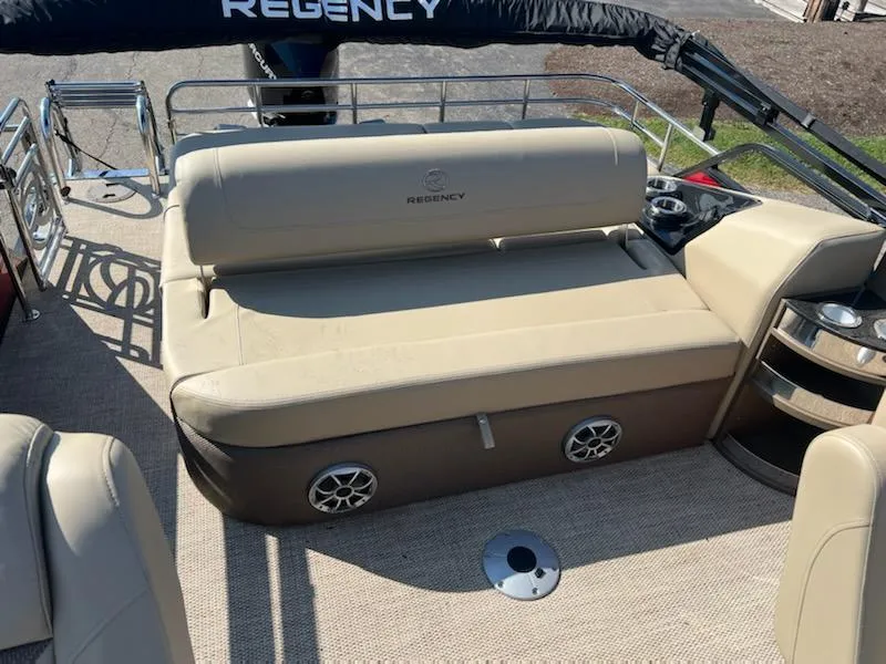 Slide: The Image of 2023 Regency 230 LE3 Sport boat interior with beige seating and speakers. - 7