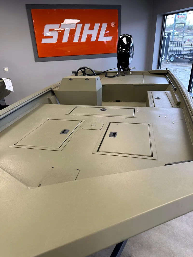 Slide: The Image of 2023 Lowe RX16SC boat interior with storage compartments, displayed indoors near a Stihl sign. - 6