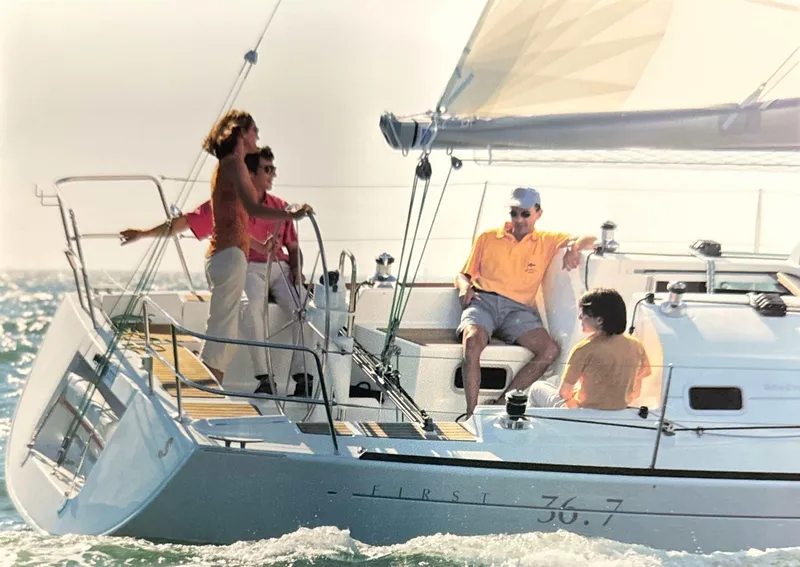 Slide: The Image of 2003 Beneteau First sailboat with people enjoying a sunny day on the water. - 1