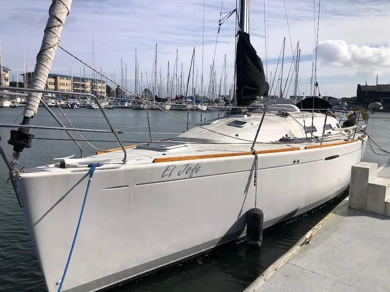 Slide: The Image of 2003 Beneteau First sailboat docked in a marina, surrounded by other boats. - 6