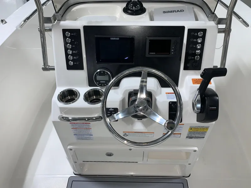 Slide: The Image of 2024 Robalo R180 Center Console boat dashboard with Simrad electronics and steering wheel. - 11