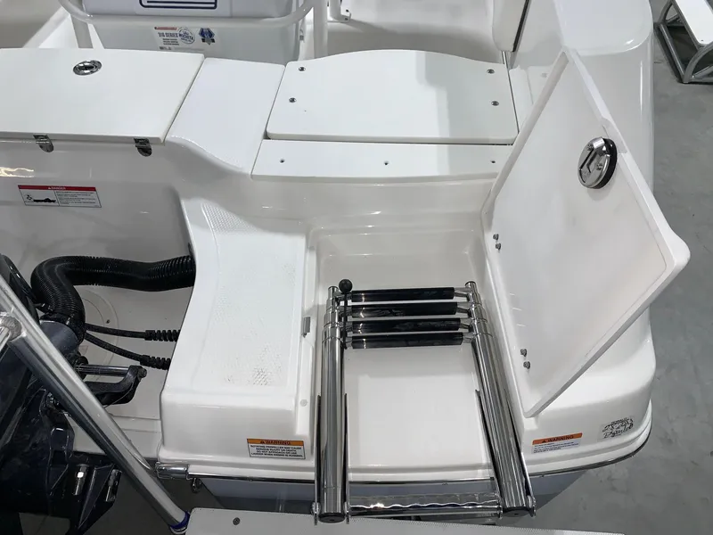 Slide: The Image of 2024 Robalo R180 Center Console boat with open storage compartment and retractable ladder. - 2