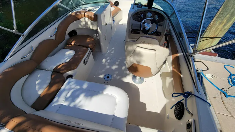 Slide: The Image of 2007 Sea Ray SunDeck 200 boat interior with tan and white seating, docked by water. - 10
