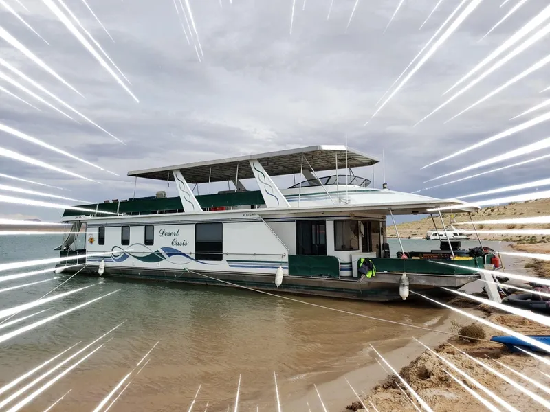Slide: The Image of 2001 Stardust Cruisers Desert Oasis houseboat docked on sandy shore under cloudy sky. - 0
