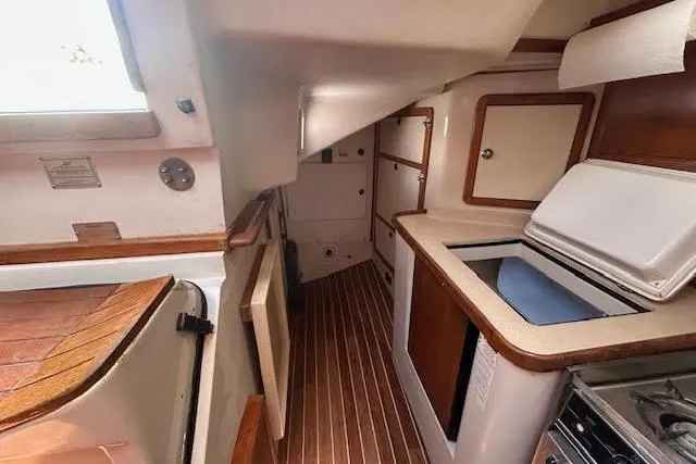 Slide: The Image of Interior of 2000 Catalina 42 Mk II sailboat, featuring compact kitchen with wood accents. - 24