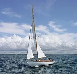 Slide: The Image of 1929 Herreshoff Fishers Island 31 sailboat on open water under a blue sky. - 12