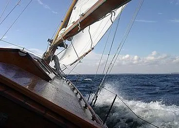 Slide: The Image of Sailing Herreshoff Fishers Island 31, 1929 model, cutting through waves under a clear sky. - 16