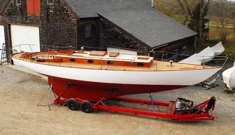 Slide: The Image of 1929 Herreshoff Fishers Island 31 sailboat on red trailer near rustic building. - 23