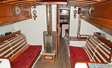 Slide: The Image of 1929 Herreshoff Fishers Island 31 yacht interior with wood paneling and red cushioned seating. - 25