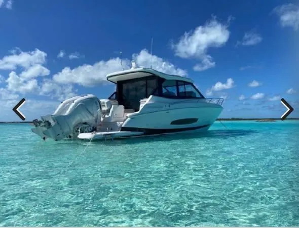 Slide: The Image of 2023 Regal 36 XO yacht anchored in clear turquoise waters under a blue sky. - 2