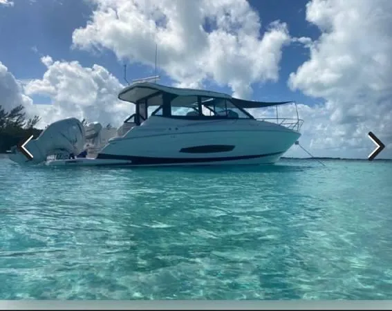 Slide: The Image of 2023 Regal 36 XO boat anchored in clear turquoise water under a partly cloudy sky. - 3