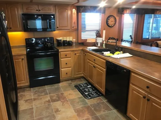 Slide: The Image of Modern kitchen in a 2007 Thoroughbred houseboat with wooden cabinets and black appliances. - 13