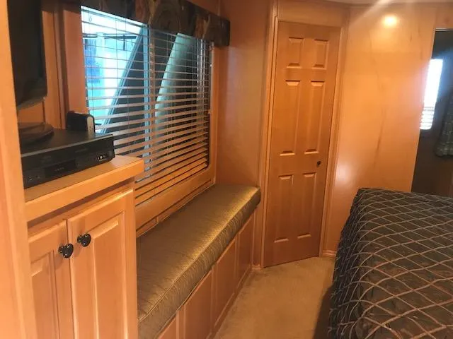 Slide: The Image of 2007 Thoroughbred houseboat interior with wood paneling, window seat, and TV cabinet. - 25